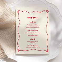 a white plate with a red menu on it next to a piece of cloth and a napkin