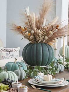 a dining room table set for thanksgiving with pumpkins and gourds