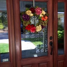 the front door is decorated with wreaths and flowers on it's glass panels