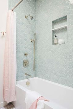 a white bath tub sitting next to a shower with a pink towel hanging on it