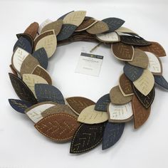 a close up of a wreath made out of leather and wood leaves on a white background