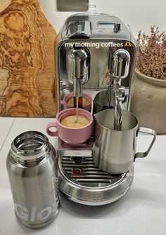 there is a coffee maker and some cups on the table with it's lid open