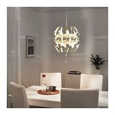 a modern chandelier hanging over a dining room table with white chairs and a vase