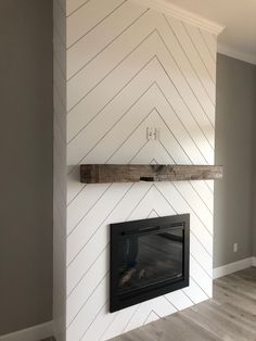 an empty room with a fireplace and white chevroned wallpaper on the walls