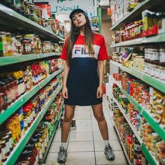 a woman standing in the aisle of a grocery store surrounded by shelves full of food