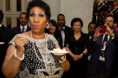 a woman in black and white dress holding a plate with cake on it while surrounded by other people