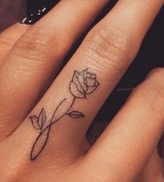 a woman's hand with a small rose tattoo on the middle finger and an arrow