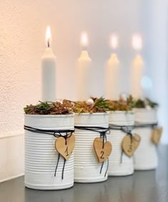 three white buckets filled with plants and hearts tied to the handles, sitting on a counter