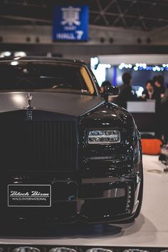 a black rolls royce parked in a showroom