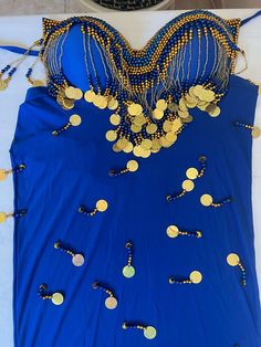 a blue dress with gold coins on it and some beads hanging off the back of it