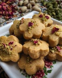 a white plate topped with cookies covered in sprinkles and flowers on top of a table