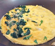 an omelet with spinach and cheese in a frying pan