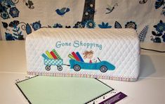 a quilted bag with a blue car carrying books on it and a notepad next to it