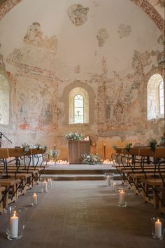 the interior of an old church with pews, candles and flowers on the alter