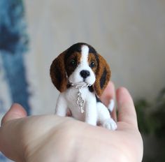 a small beagle puppy is being held in someone's hand with a keychain