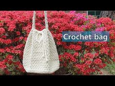 a crochet bag hanging on a bush with flowers in the background and text that reads, crochet bag