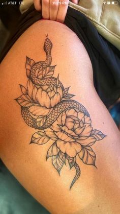 a woman's thigh with a snake and roses tattoo on it