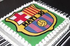 a cake decorated with the emblem of a soccer team on top of a piano keyboard