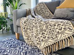 a living room with a couch, rug and potted plant on the floor in front of it