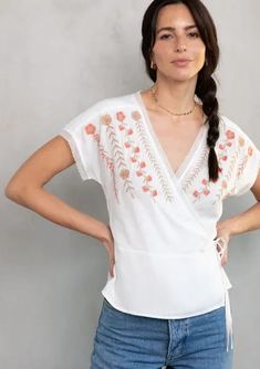 Delicate bohemian details add a pretty touch to this ultra-flattering wrap top. Featuring a wrap front, side tie closure, and lace trim. A simple and sophisticated style with embroidered detail. We love to style this warm-weather top with denim and a lace-up sandal. Vacation V-neck Top With Embroidered Hem, V-neck Vacation Tops With Embroidered Hem, Cotton Wrap Top For Summer, Spring Surplice Neckline Faux Wrap Top, White Tie Waist Top For Vacation, V-neck Wrap Top For The Beach, Chic White Wrap Top, Spring White Wrap Top, White Wrap Top For Spring