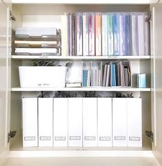 a book shelf filled with lots of books and binders on top of white shelves