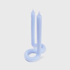 two blue candles sitting next to each other on top of a white surface with one candle in the middle