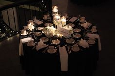 the table is set with candles, plates and silverware for an elegant wedding reception