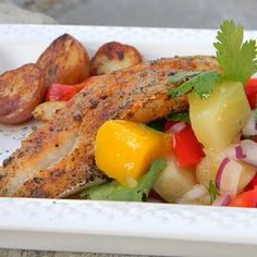 a white plate topped with meat and veggies next to potato wedges on top of a table