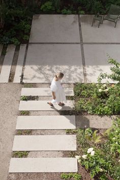 a person walking up some steps in the middle of a garden with trees and bushes