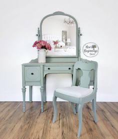 a vanity with a mirror, chair and vase on it