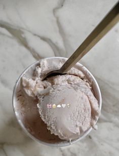 a scoop of ice cream with a spoon in it on a marble counter top,