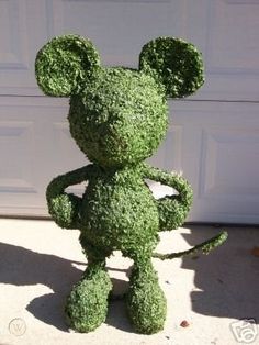 a green teddy bear made to look like a mouse sitting in front of a garage door