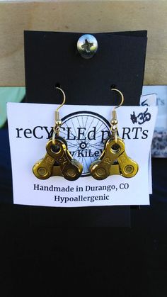 two pairs of earrings are on display in front of a sign that says recycled arts and ride