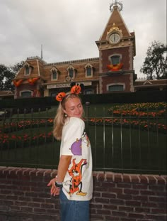 a woman standing in front of a building with a clock on it's face