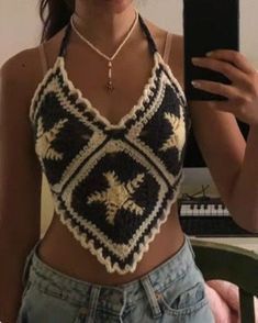 a woman taking a selfie with her cell phone wearing a crocheted crop top