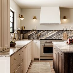 a kitchen with white cabinets and marble counter tops, along with an oven in the center