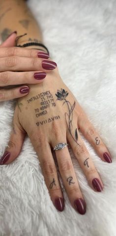 a woman's hand with tattoos on it and her name written on the ring finger