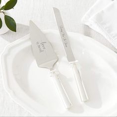 two personalized knifes on a white plate next to a green plant in a vase