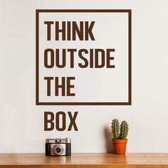 a wall decal that says think outside the box with a camera next to it