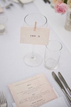 the table is set with silverware and place cards