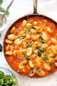 a skillet filled with pasta and garnish next to other dishes on a table