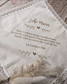 an embroidered handkerchief with the words jube mama written in german on it and a feather