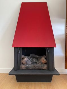 a fire place with logs in it and a red cover over the top that is sitting on a hard wood floor