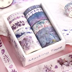 four rolls of washi tape in a box on a table with flowers and clocks