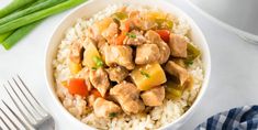 a white bowl filled with rice, meat and veggies next to green beans