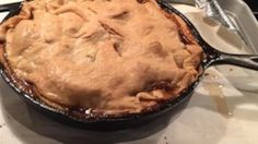 a pie sitting in a pan on top of a table next to a knife and fork