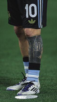 the legs and feet of a soccer player with tattoos on his leg, wearing black shorts