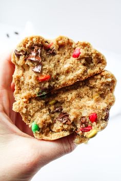 a person holding two cookies in their hand with candy on the top and chocolate chips on the bottom