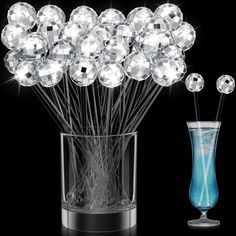 a vase filled with lots of crystal balls next to a tall glass cup full of water