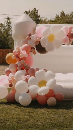 a bed in the grass with balloons attached to it's sides and flowers on top